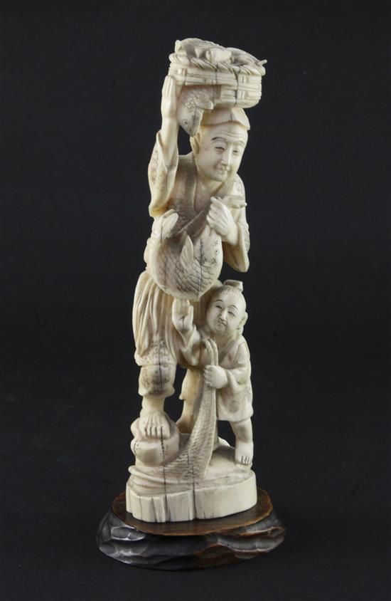 A Japanese walrus ivory group of a fisherman and a boy, early 20th century 21.5cm, wood stand